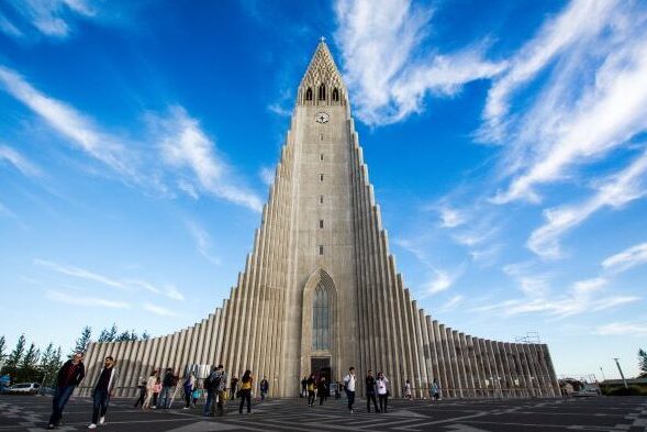 Frontal picture of the largest church in Iceland, known for its distinctively curved spire and side wings.