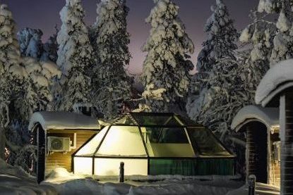 Glass igloo at night time with snow and northern light