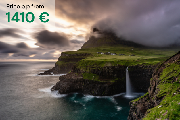 Waterfall into the ocean with clouds covering the mountains