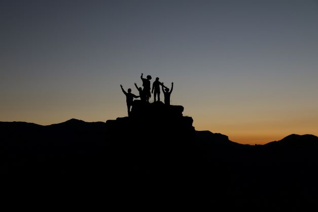 Happy group of people on the top of mountain enjoying the sunrise