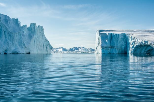 Icebergs on calm water with clear blue sky